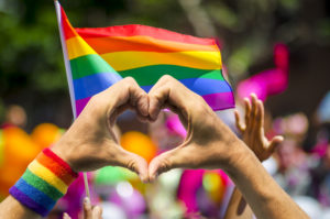 heart hands in front of rainbow flag
